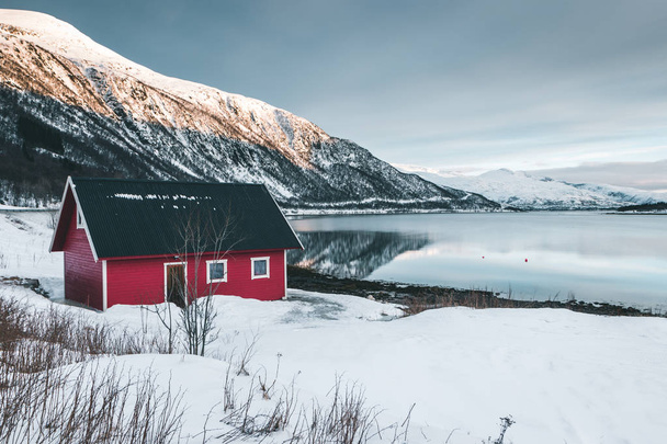 Red house on the lake above the mountains. Splendid landscape of Lofoten Islands, Norway - Fotó, kép