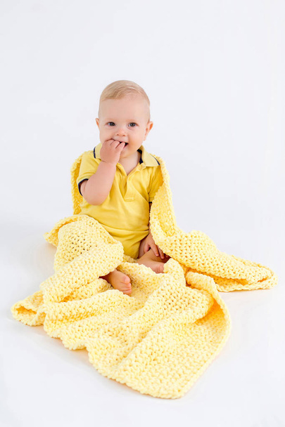 Kid no cobertor amarelo de pelúcia no fundo branco
 - Foto, Imagem