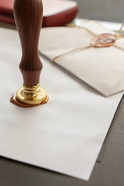 Notary public wax stamper. White envelope with brown wax seal, golden stamp. Responsive design mockup, flat lay. Still life with postal accessories. - Foto, Imagen