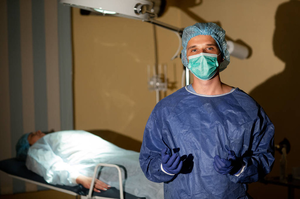 Egy nyugodt sebész fényképe egy beteggel a háttérben. Műtétre való felkészülés - Fotó, kép