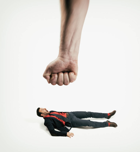 The big human fist bring down the man off his feet. Concept of unexpected problems which gets knocked down. - Photo, Image