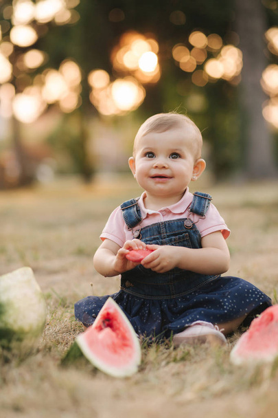 Portrét nádherné holčičky, která jedla meloun. Dítě žere meloun v zahradě. Rozkošná holčička, která si hraje na zahradě a kouše si kus melounu - Fotografie, Obrázek