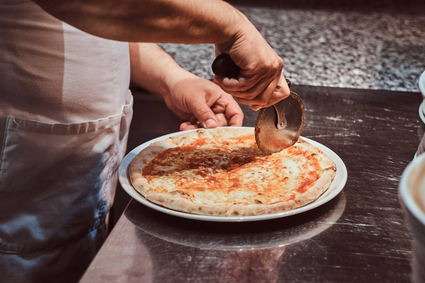Chef coupe pizza fraîchement préparée
 - Photo, image