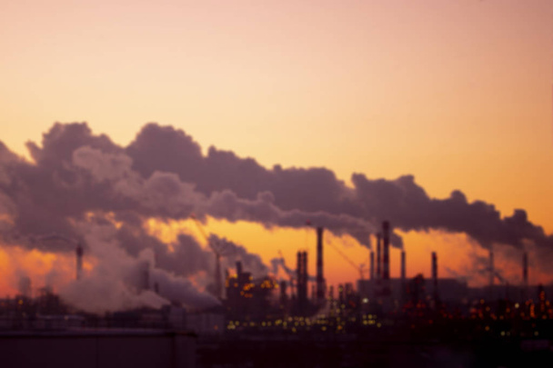 日没時のパイプからの紫色の煙、ぼやけた産業風景。環境問題と大気汚染 - 写真・画像
