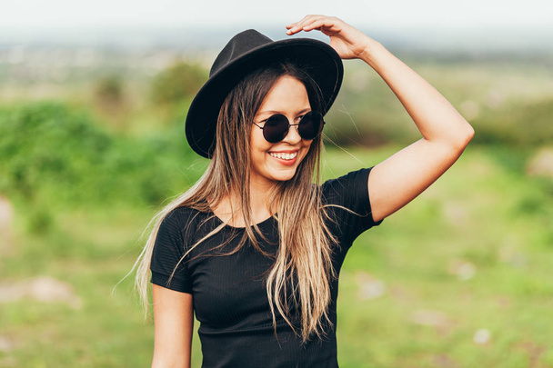 Retrato de mujer joven con sombrero fedora y gafas de sol
 - Foto, Imagen