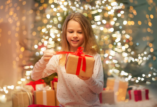 smiling girl with christmas gift at home - Foto, Bild