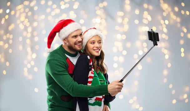 happy couple in christmas sweaters taking selfie - Fotó, kép