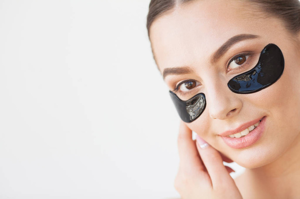 Patch Under Eyes. Beautiful Woman Face With Black Hydrogel Patches, Lifting Anti-Wrinkle Collagen Mask On Fresh Healthy Facial Skin. - Photo, Image