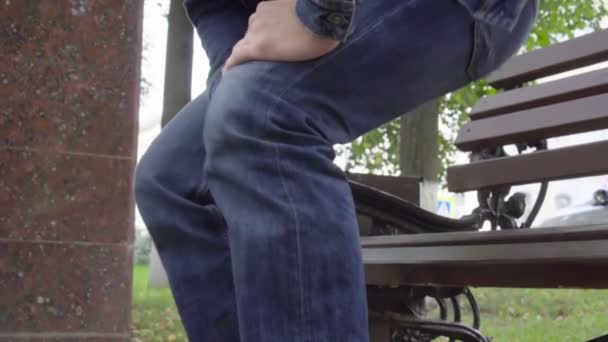 Man standing up from bench feeling sharp knee pain in park, osteoarthritis, injury - Felvétel, videó
