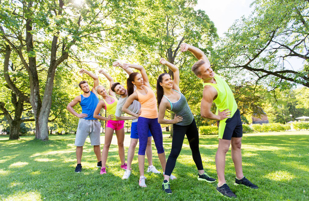 group of happy people exercising at summer park - Фото, зображення