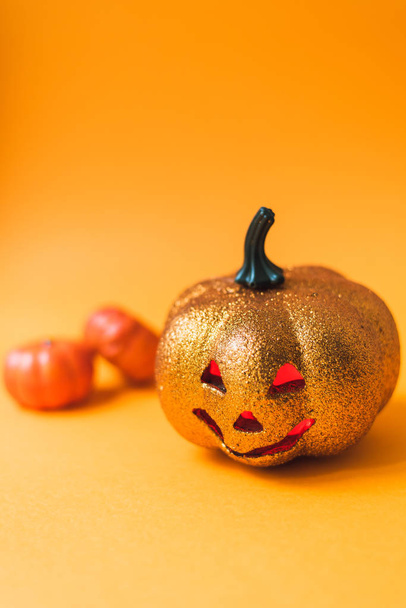 Straszny błyszczący Halloween dynia zabawka. Jack-o '-latarnia na pomarańczowym tle z czerwonymi świecącymi oczami z miejscem na tekst - Zdjęcie, obraz