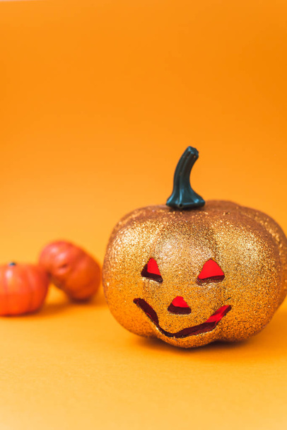 Espeluznante juguete de calabaza de Halloween brillante. Jack-o '-linterna sobre un fondo naranja con ojos rojos luminosos con un lugar para el texto
 - Foto, Imagen