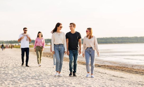 happy friends walking along summer beach - Foto, immagini