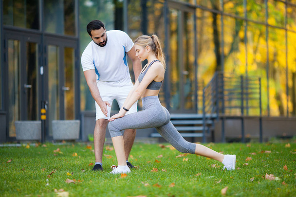 Fitness. Entrenador personal toma notas mientras la mujer hace ejercicio al aire libre
 - Foto, Imagen