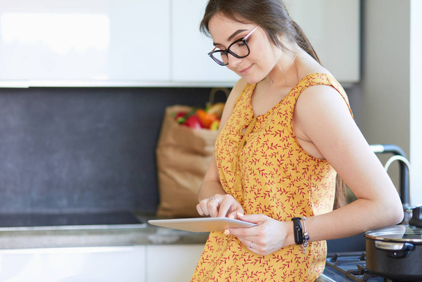 beautiful young woman using a digital tablet in the kitchen - Photo, Image