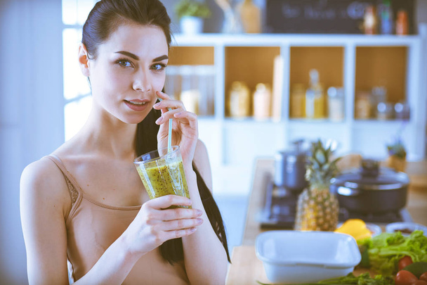 Young woman with glass of tasty healthy smoothie at table in kitchen - Фото, изображение