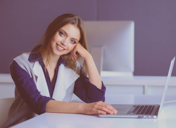 Young confident businesswoman working at office desk and typing with a laptop - Foto, immagini