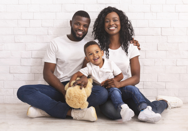 若い黒人の両親とその息子は一緒に床に座っている - 写真・画像