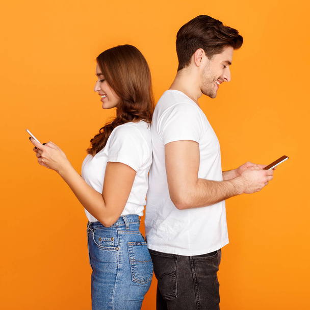 Νεαρό ζευγάρι που χρησιμοποιεί κινητά, στέκεται πίσω στο πίσω μέρος - Φωτογραφία, εικόνα