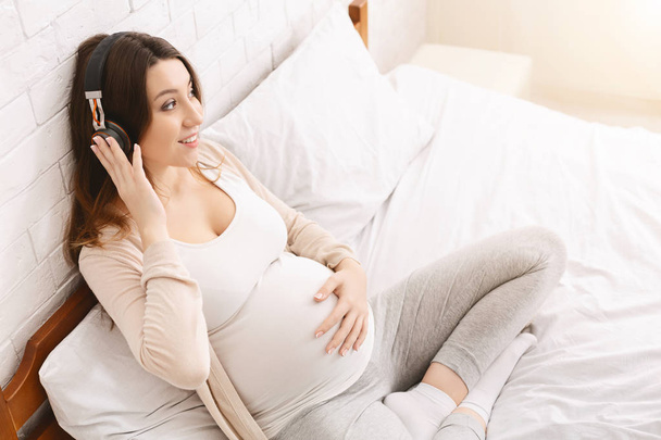 Tranquillo donna incinta ascoltare musica con cuffie wireless
 - Foto, immagini