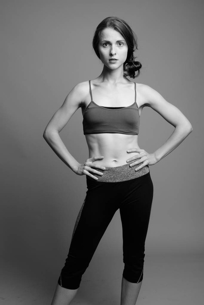 Young beautiful woman ready for gym against gray background - Photo, Image