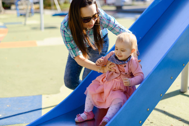 Mother and little daughter are walking and playing on the playground in the park - Foto, Imagen