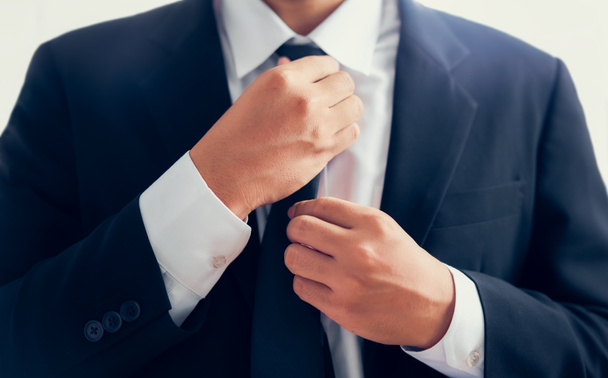 Businessman in black suit and adjusting necktie. - Photo, Image