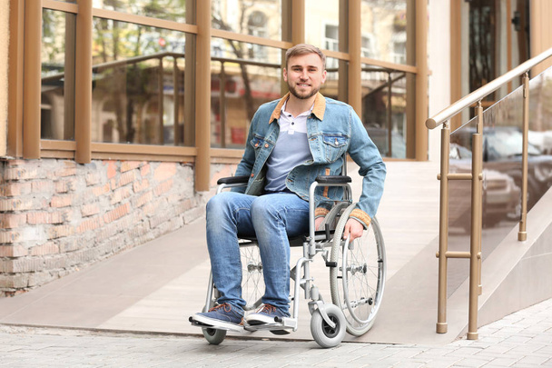 Young man in wheelchair using ramp at building outdoors - Φωτογραφία, εικόνα