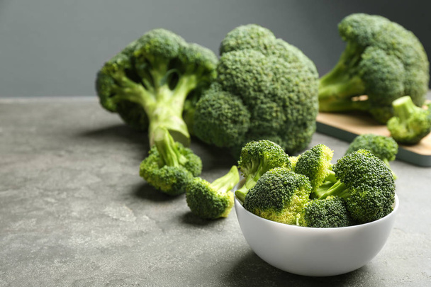 White bowl of fresh green broccoli on grey stone table, space for text - Foto, imagen