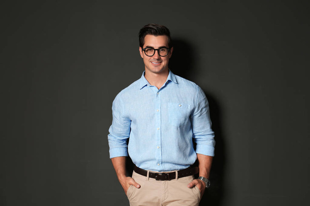 Handsome young man in stylish clothes with glasses on dark background - Zdjęcie, obraz