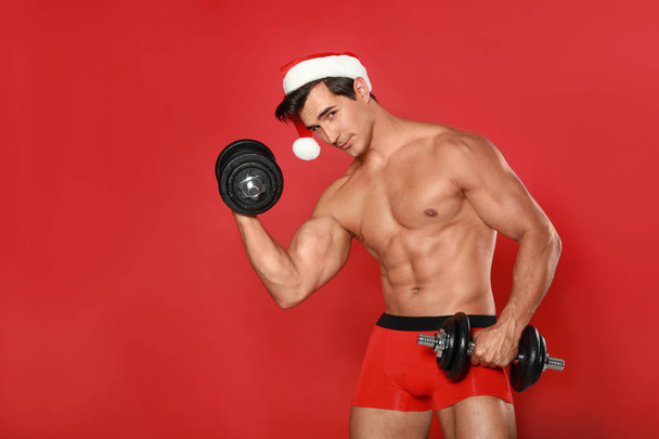 Sexy shirtless Santa Claus with dumbbells on red background - Zdjęcie, obraz
