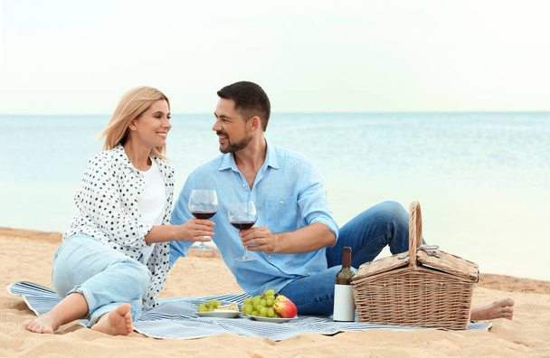 Happy romantic couple having picnic at beach - Foto, Imagen