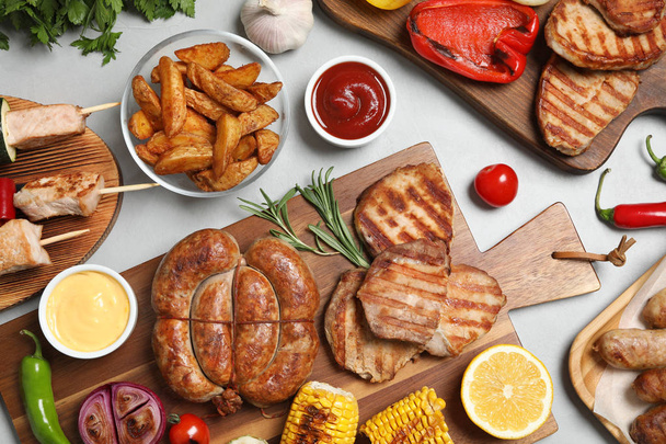 Flat lay composition with barbecued meat and vegetables on light table - Foto, imagen