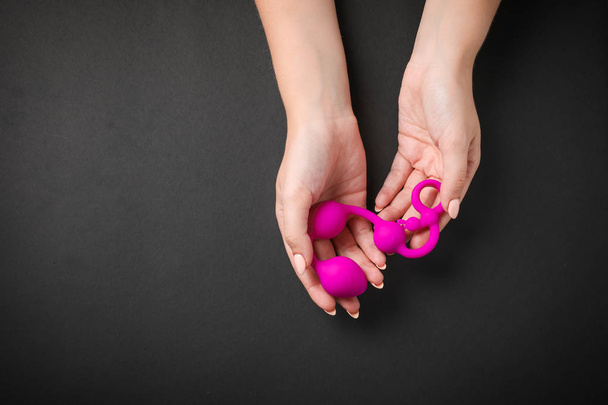 Young woman holding pink anal balls on black background, top view with space for text. Sex toy - Photo, image