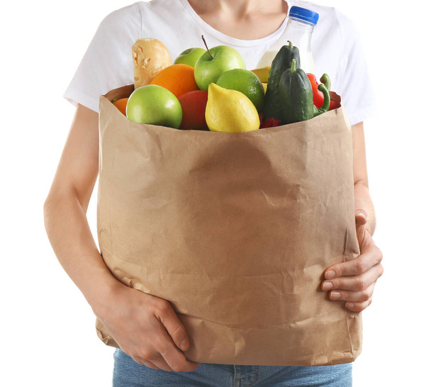 Woman holding paper bag with different groceries on white background, closeup view - Фото, зображення