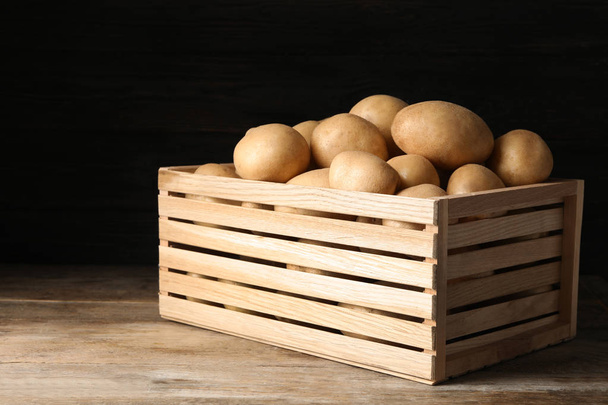Raw fresh organic potatoes on wooden table against dark background - Fotoğraf, Görsel