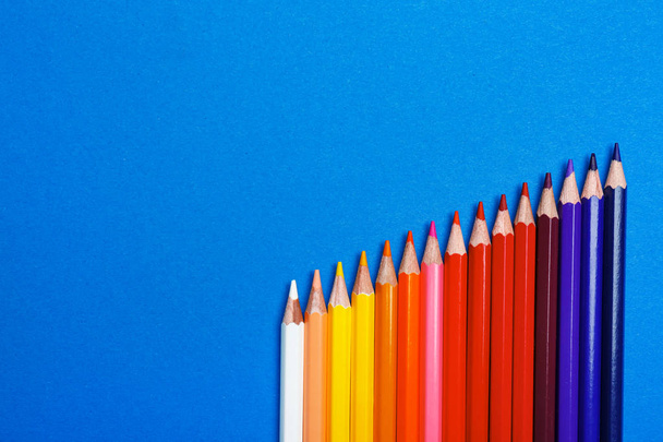 Color pencils on blue background, flat lay. Space for text - Fotó, kép
