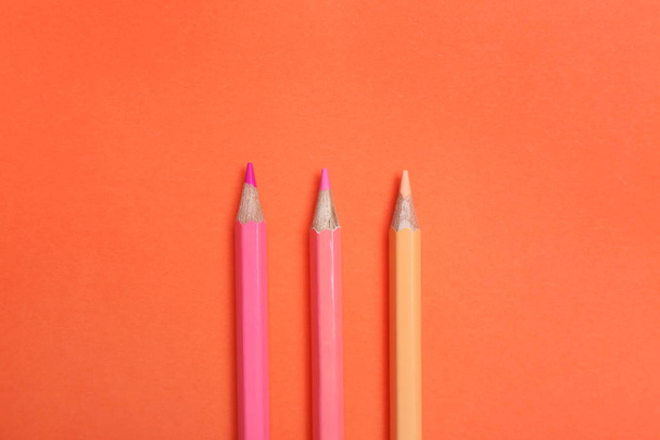 Color pencils on coral background, flat lay - Foto, afbeelding