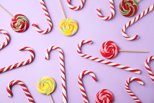 Flat lay composition with candy canes and lollipops on lilac background - Fotoğraf, Görsel