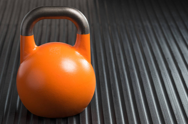 Kettlebell de levantamiento de pesas naranja de 28 kg dentro de un gimnasio
 - Foto, Imagen