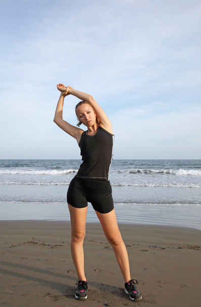 Woman stretching on the beach - Foto, imagen