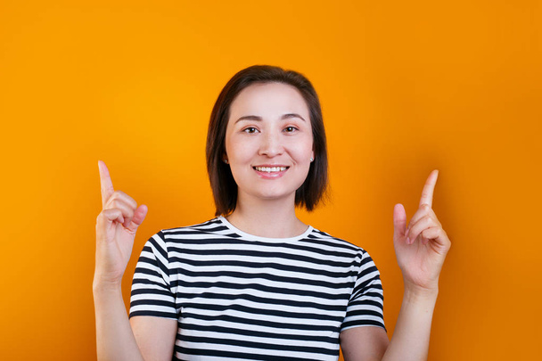 Ritratto di giovane donna asiatica sorridente sopra giallo, mostrando rivolta verso l'alto e lato con le dita, copiare lo spazio
 - Foto, immagini