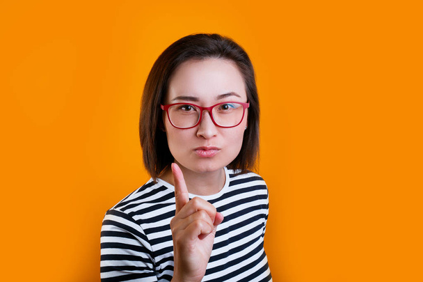 displeased asian woman in red glasses warning over yellow background - Photo, image