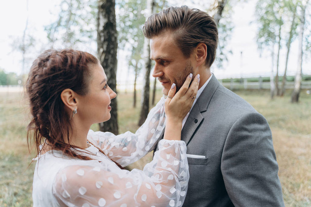 beautiful pregnant woman in white dress with handsome man face to face in Birch Grove     - 写真・画像