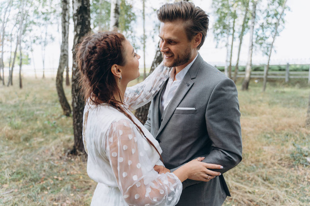 beautiful pregnant woman in white dress with handsome man face to face in Birch Grove  - Photo, Image
