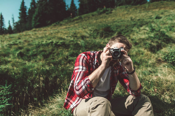 Traveler man taking shot by camera on green hill - Foto, Imagen