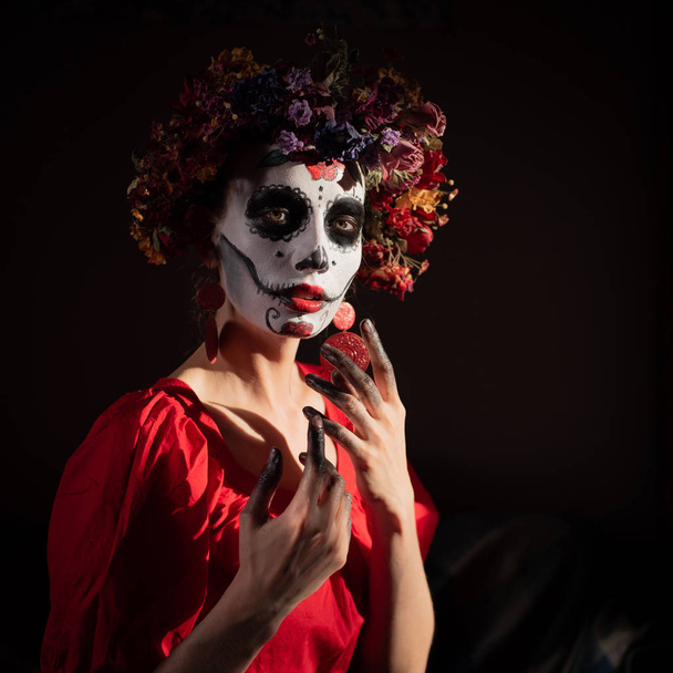 Portrait of a girl with makeup for halloween skull and flowers on her head for the holiday da de los muertos - Fotó, kép