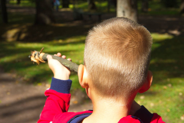 A boy plays with a stick-gun. Children's game of shooting outdoor - Fotó, kép