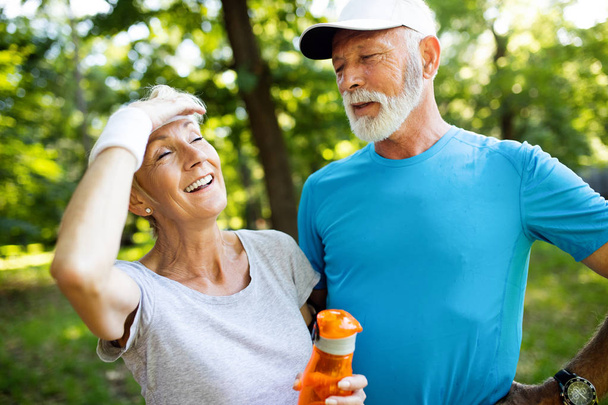 Active senior couple running in the park for healthy life - Фото, изображение