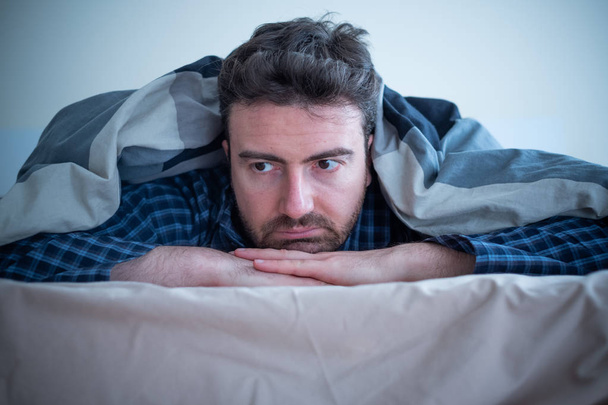 Άνδρας με το πρόβλημα του ύπνου στο κρεβάτι του στο σπίτι - Φωτογραφία, εικόνα